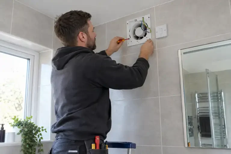 Technician fitting an extractor fan above a bathroom window